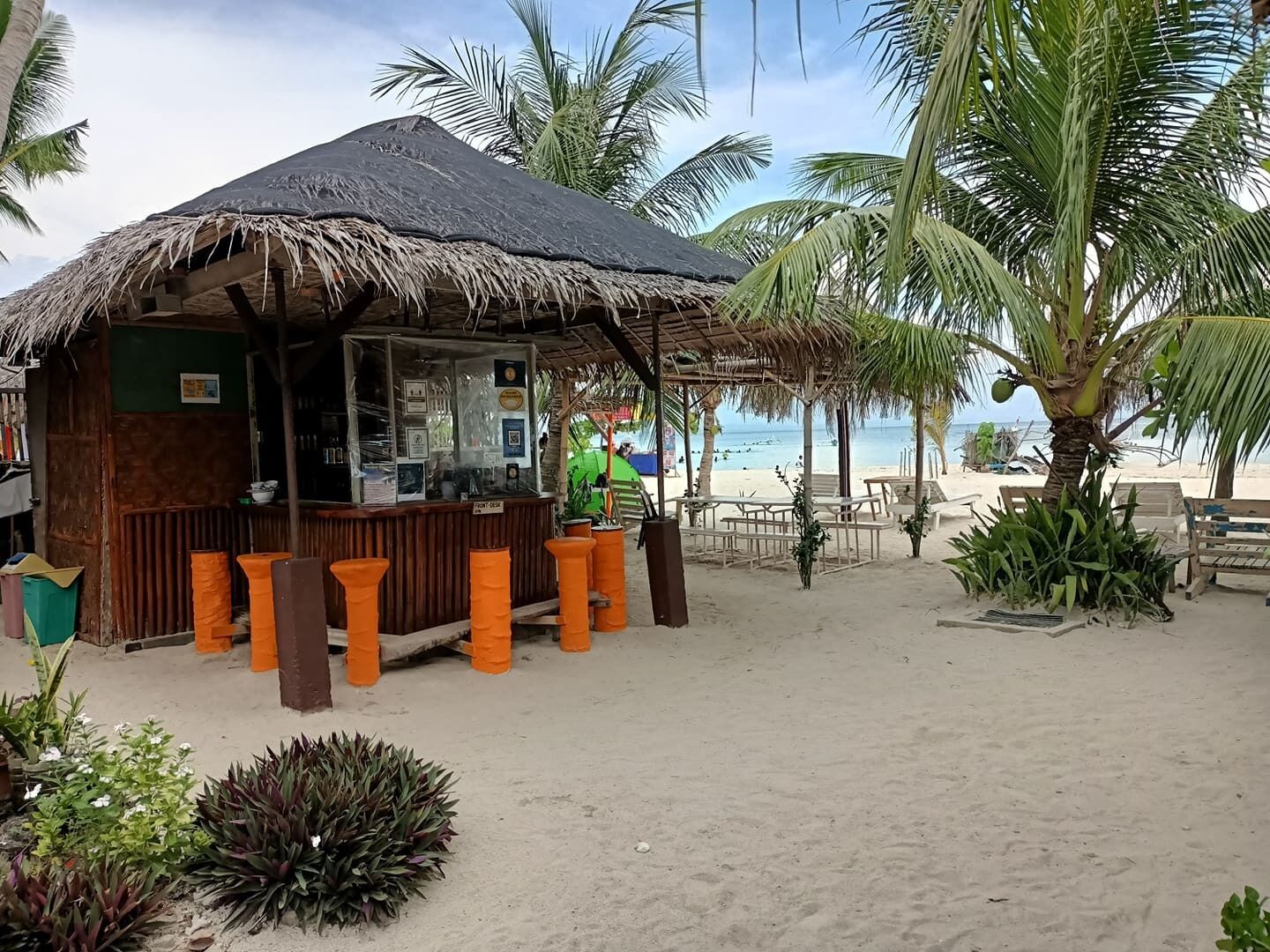 A beachside hut with a thatched roof, wooden benches, and a view of the beach and ocean.