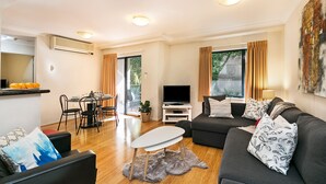 Una sala de estar moderna con un sofá, una mesa de comedor y un televisor.