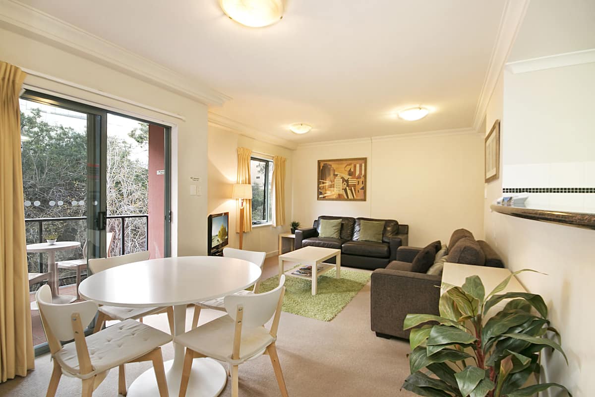 A living room with a white table, chairs, a grey sofa, and a green plant.