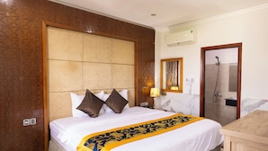 A hotel room with a large bed, a wooden headboard, a shower, and a wooden desk. - Atana Airport Hotel (Ho Chi Minh City)