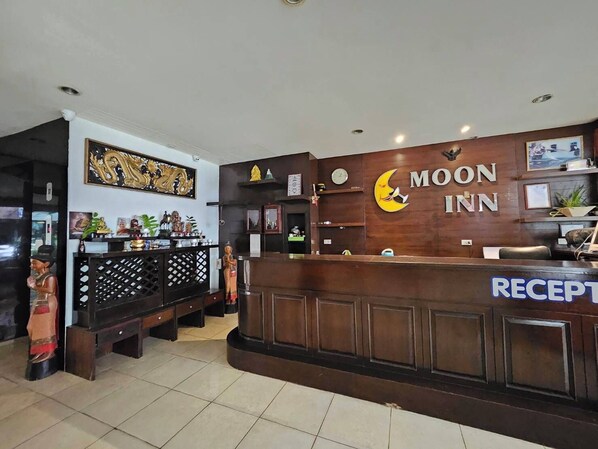 A reception area with a wooden counter, a clock, and a sign that reads "MOON INN". - Patong Moon Inn Guesthouse (Patong)