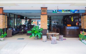 A hotel lobby with a reception desk, seating area, and a sign for 'Moon Travel'. - Patong Moon Inn Guesthouse (Patong)