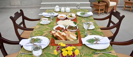 A dining table set with various dishes, a vase of flowers, and wicker chairs.