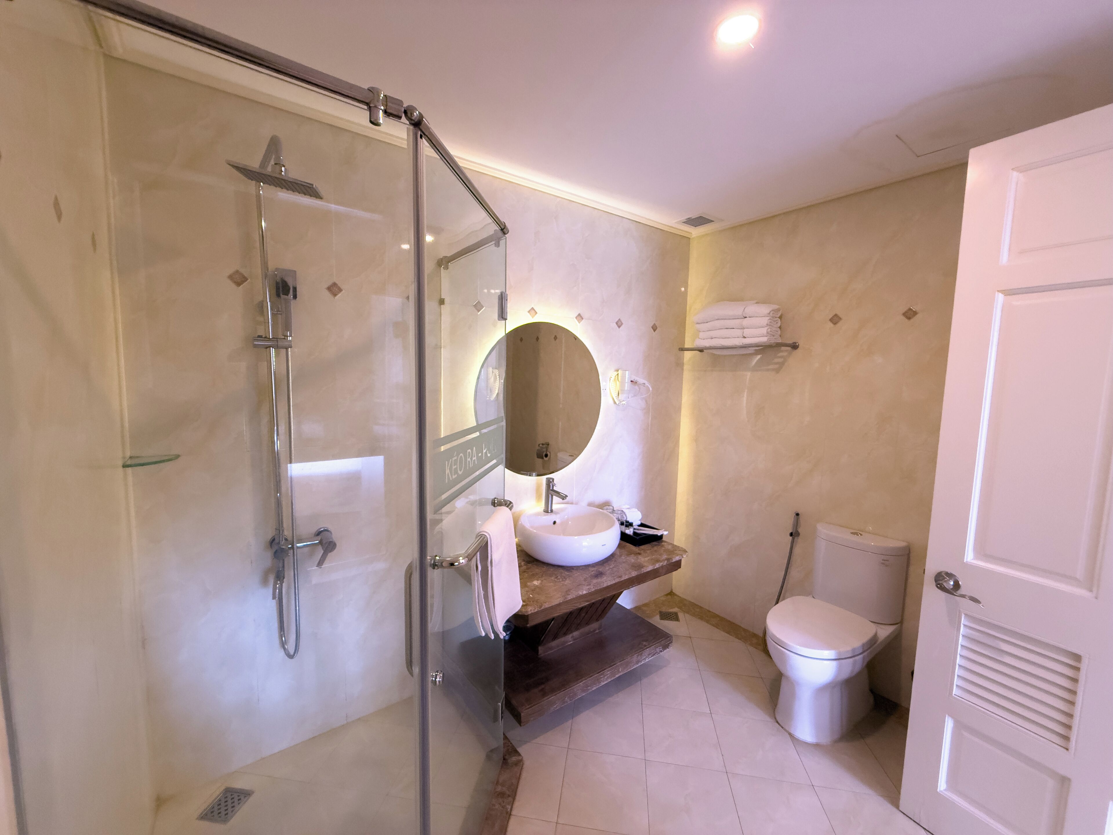 A bathroom with a glass-enclosed shower, a sink with a mirror, and a toilet.