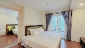 Een hotelkamer met een groot bed, een nachtkastje, een lamp en uitzicht op het balkon.