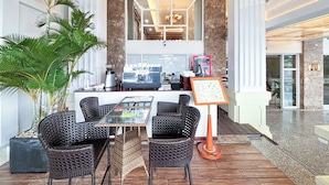 Een hotellobby met een zithoek, een koffieapparaat en een menukaartstandaard.