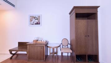 Una habitación con un banco de madera, una mesita con una tetera y botellas, una silla, un armario de madera y un par de zapatos en una caja de zapatos.