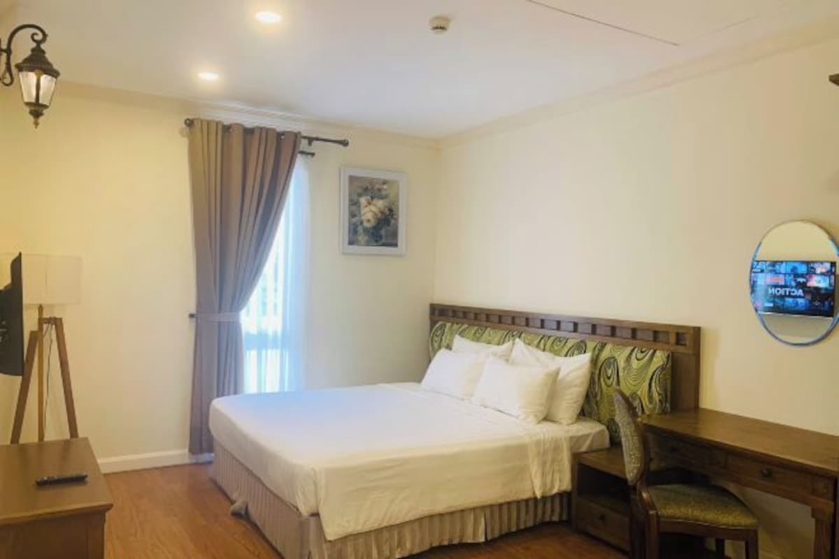 Une chambre d’hôtel avec un lit, un bureau, une chaise, une lampe et un téléviseur.