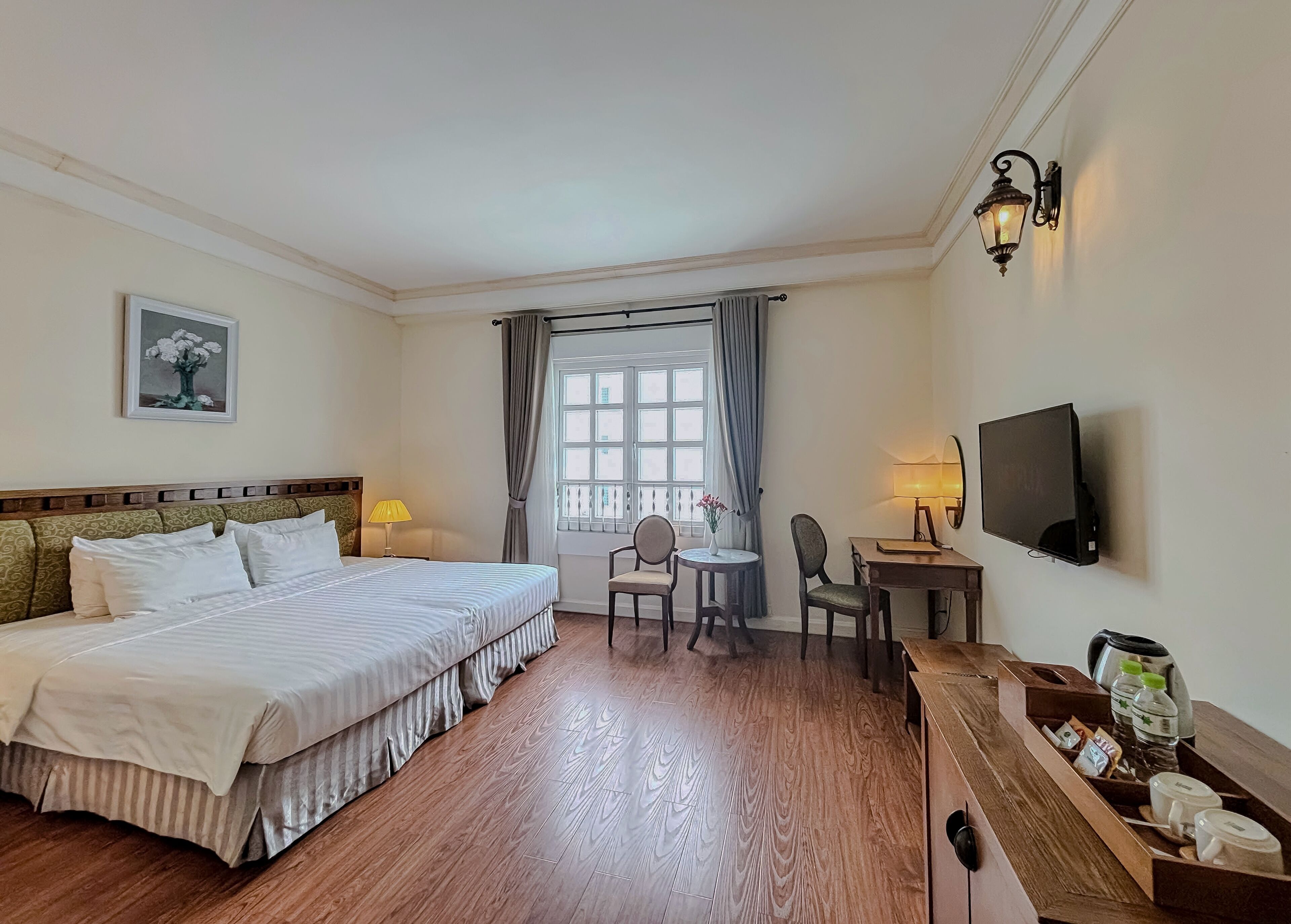 Une chambre d’hôtel avec un lit double, un bureau avec une chaise, une télévision et une petite table avec une lampe.
