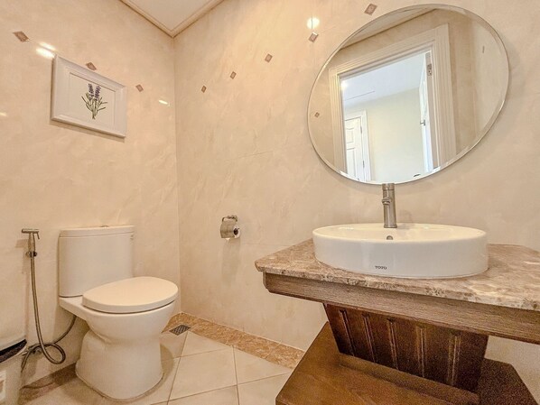 Une salle de bain avec des toilettes, un lavabo avec un miroir et un tableau encadré au mur.