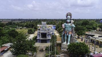 A large statue of a deity in front of a temple with a traditional architectural style.