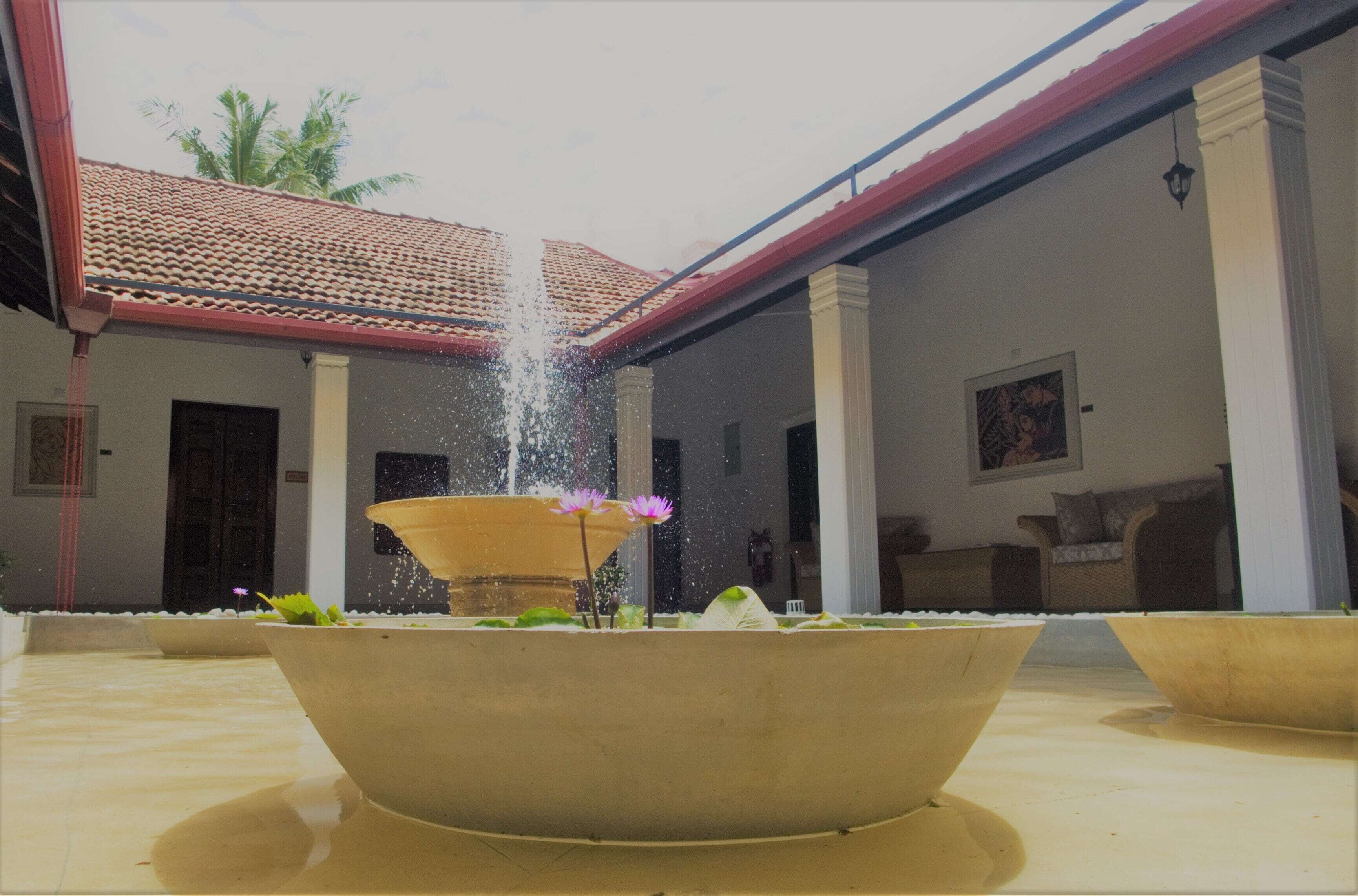 A courtyard with a central fountain, surrounded by columns and a tiled roof.