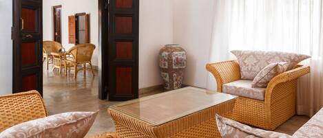 Una habitación con muebles de mimbre, una mesa de vidrio y un jarrón tradicional.