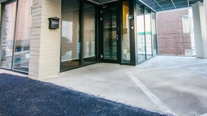A building entrance with a glass door, a sign labeled "POST", and a metal grid ceiling. - Morning Dew Guesthouse (Busan)