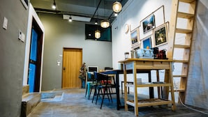 A cozy room with a wooden table, chairs, and a ladder against the wall. - Morning Dew Guesthouse (Busan)