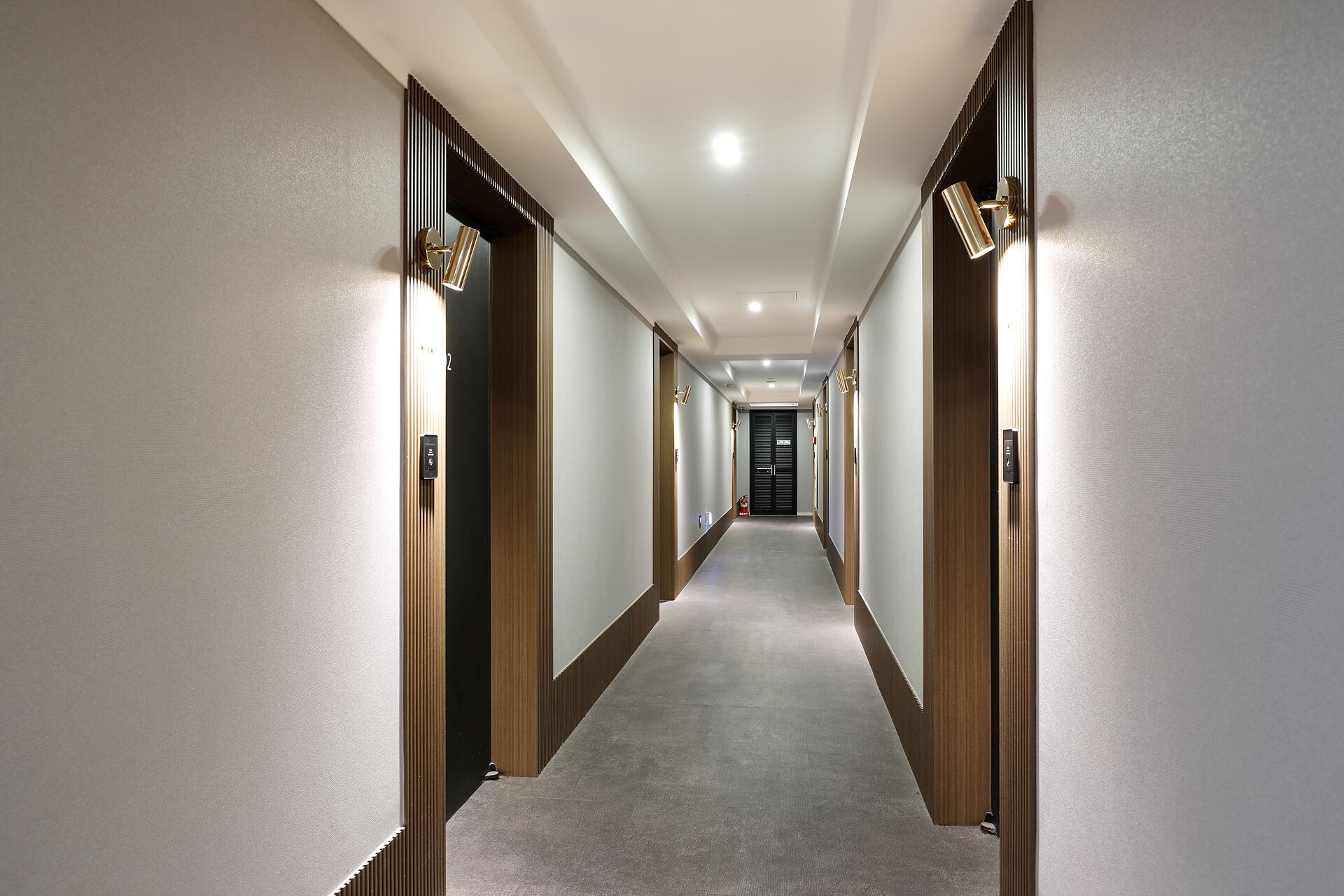 A long, narrow hotel corridor with wooden doors and a carpeted floor.