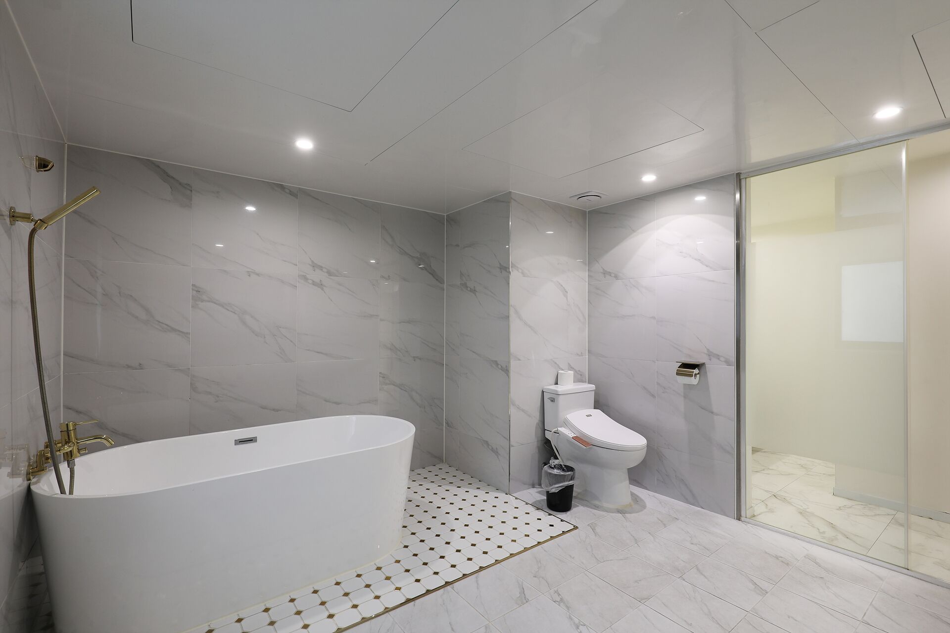 A modern bathroom with a freestanding bathtub, a toilet, and a glass shower enclosure.