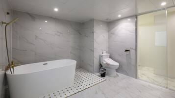 A modern bathroom with a freestanding bathtub, a toilet, and a glass shower enclosure.