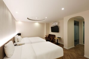 Habitación de hotel con dos camas, un televisor, una mesita y una silla.