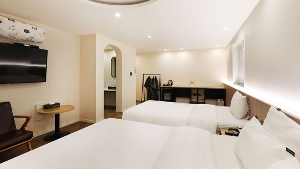 Habitación de hotel con dos camas, un televisor, un escritorio y un espejo.