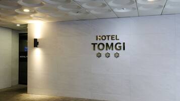 A wall with the text 'HOTEL TOMGI' and three decorative elements.