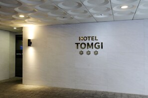 A wall with the text 'HOTEL TOMGI' and three decorative elements. - Hotel Tomgi Jamsil (Seoul)