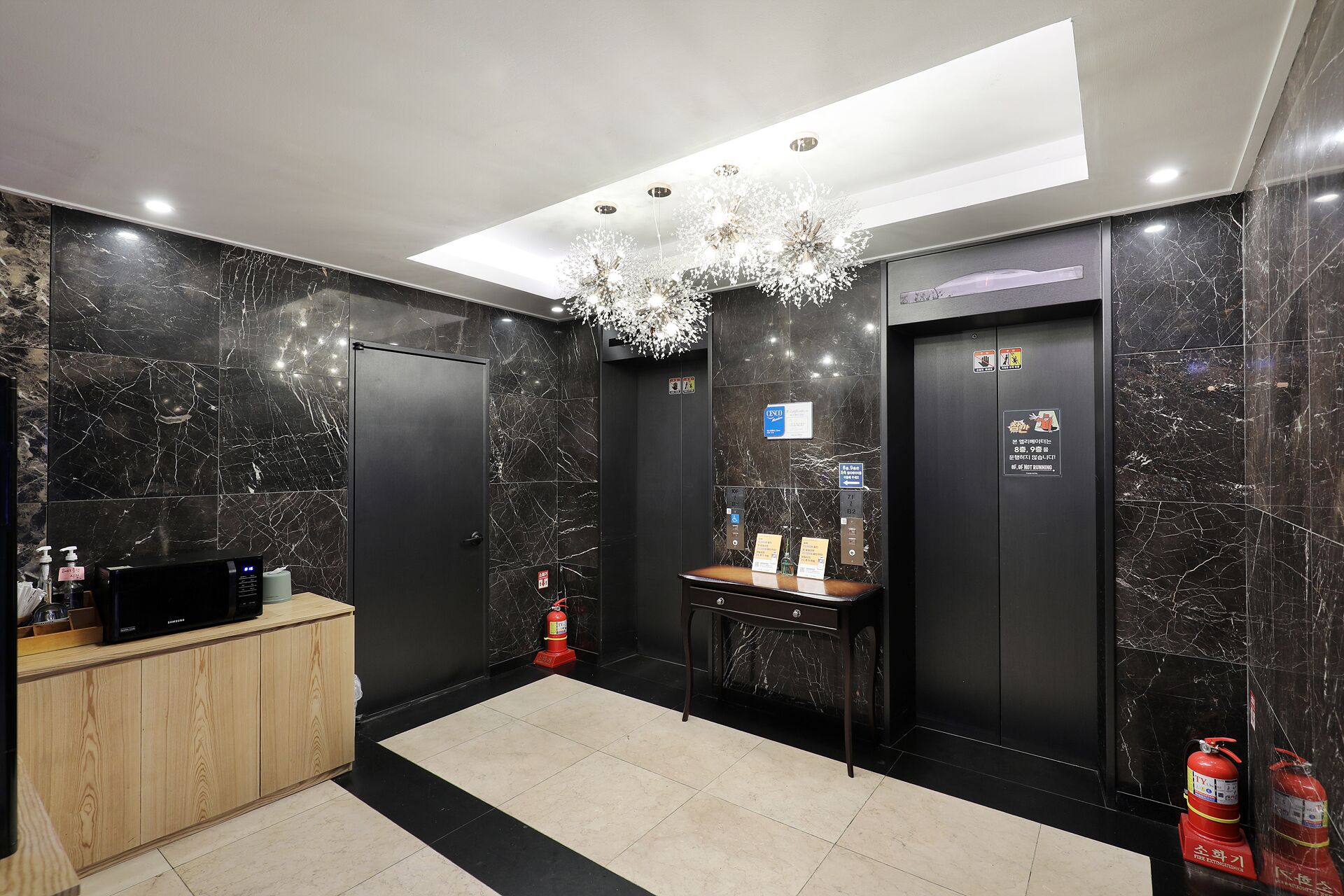 A modern elevator with marble walls, a reception desk, and a chandelier.