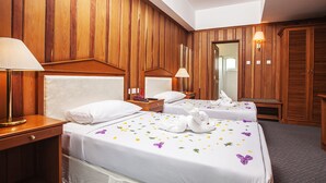 Ein Hotelzimmer mit zwei Betten, Holzvertäfelung, einem Spiegel und einem Kleiderschrank.