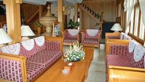 Eine geräumige Lobby mit Holzmöbeln, einer Treppe und einer großen Blumenvase.