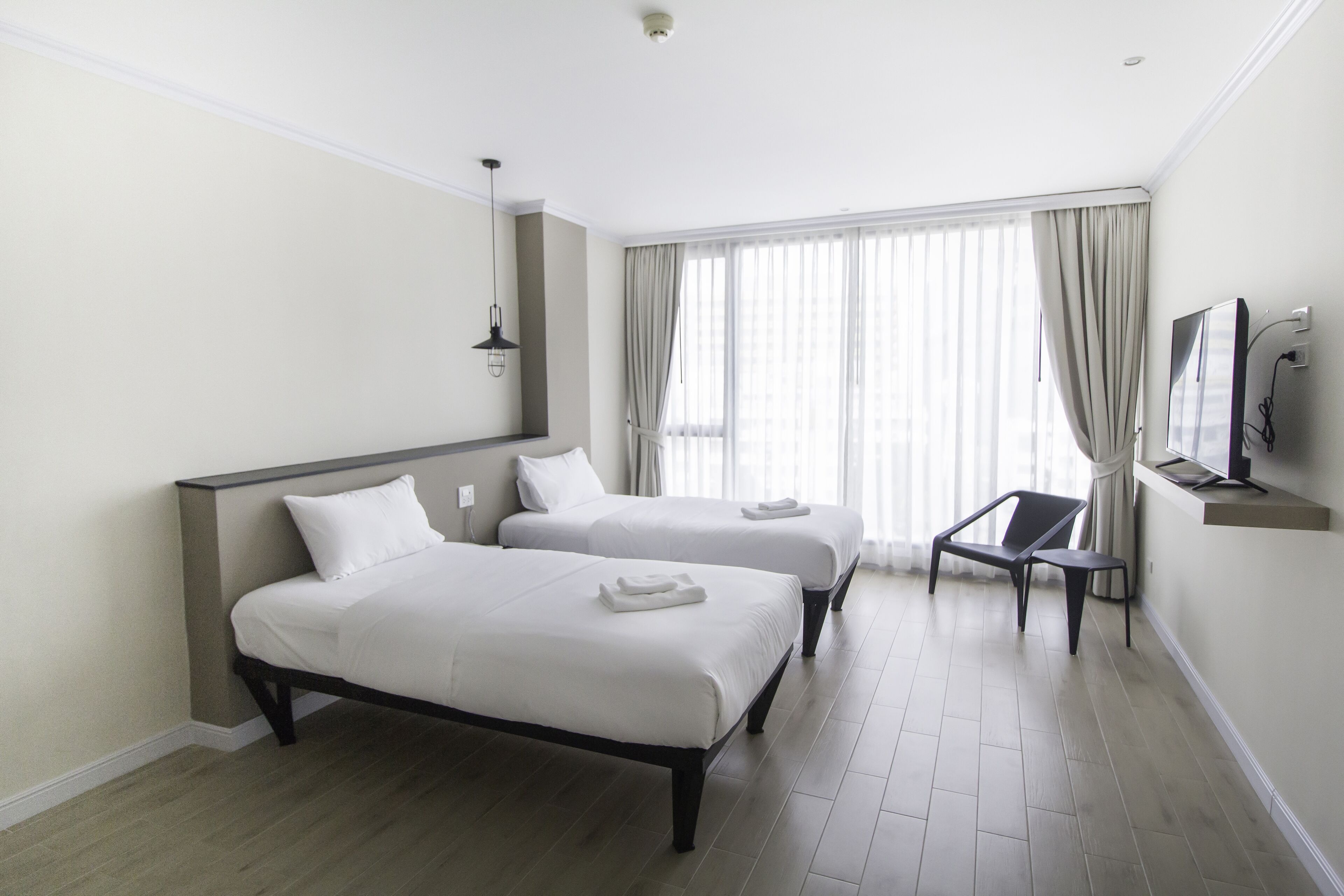Habitación de hotel con dos camas, televisión y una silla.