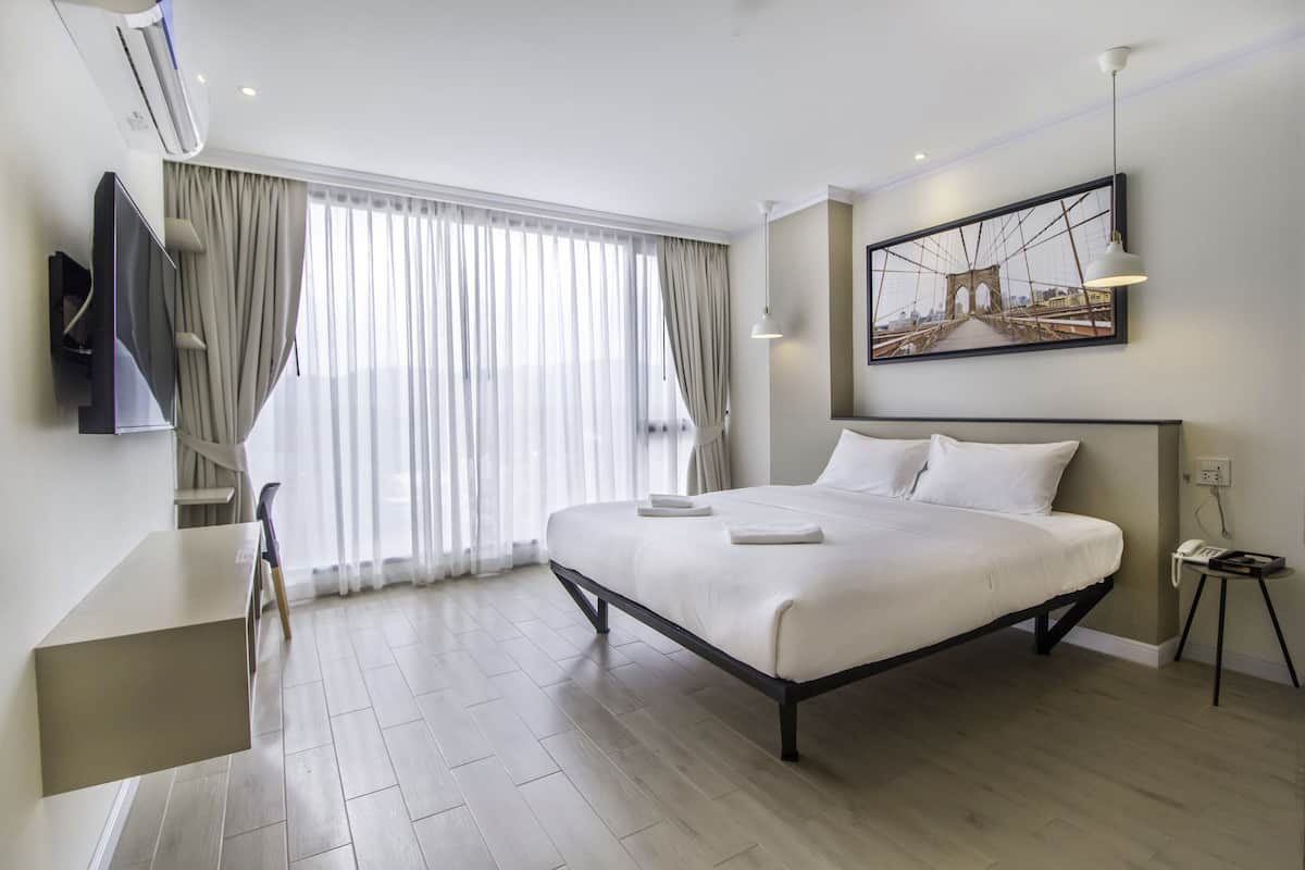 A modern hotel room with a large bed, a desk, and a television.