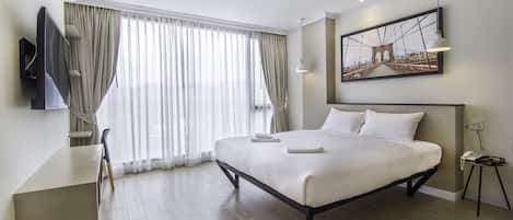 Een moderne hotelkamer met een groot bed, een bureau en een televisie.