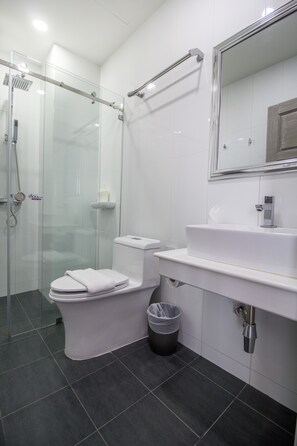 A modern bathroom with a glass-enclosed shower, a white toilet, and a sink with a mirror above it. - Hataara Hua Hin (Hua Hin)
