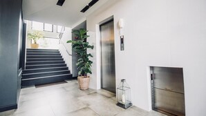 A modern interior with a staircase, a potted plant, an elevator, and a fireplace. - Hataara Hua Hin (Hua Hin)