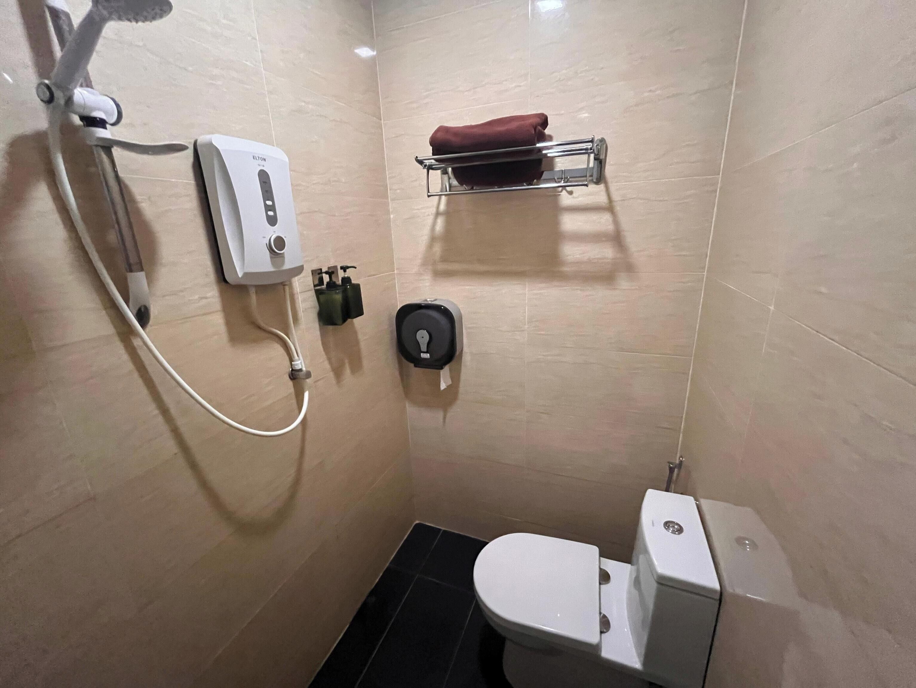 A small, modern bathroom with a toilet, a shower, and a towel rack.