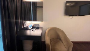 A hotel room with a bed, a desk with a lamp, a TV, and a chair. - Capital O 91074 Grand World Hotel (Masai)