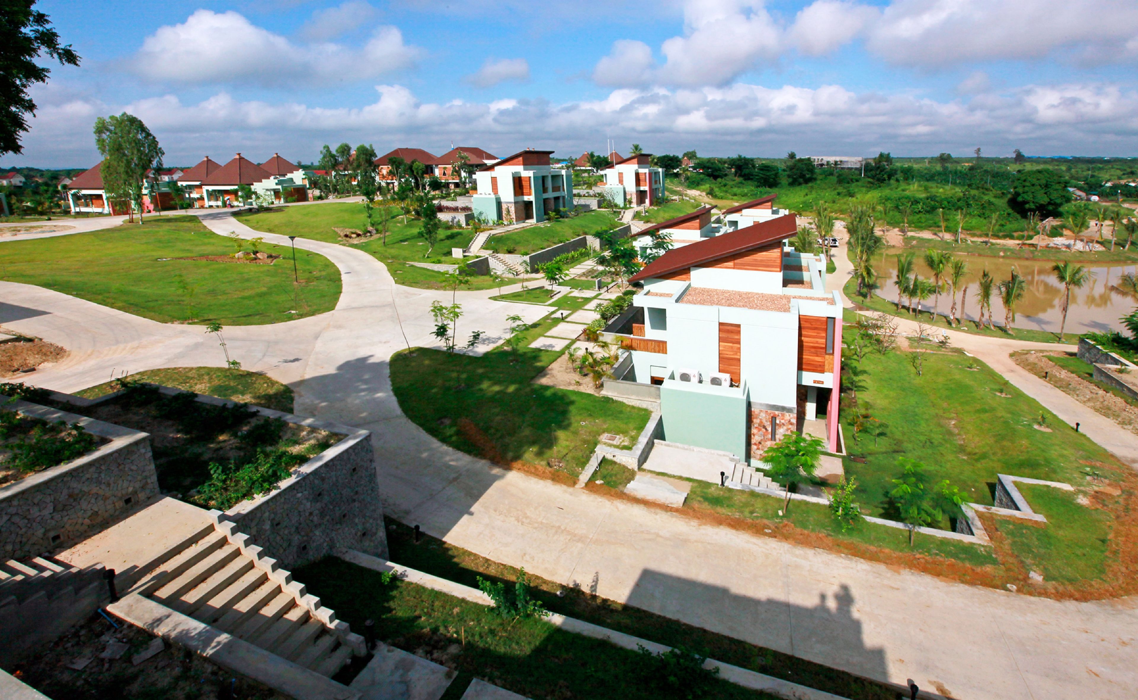 A residential area with modern houses, a curved driveway, and a small pond.