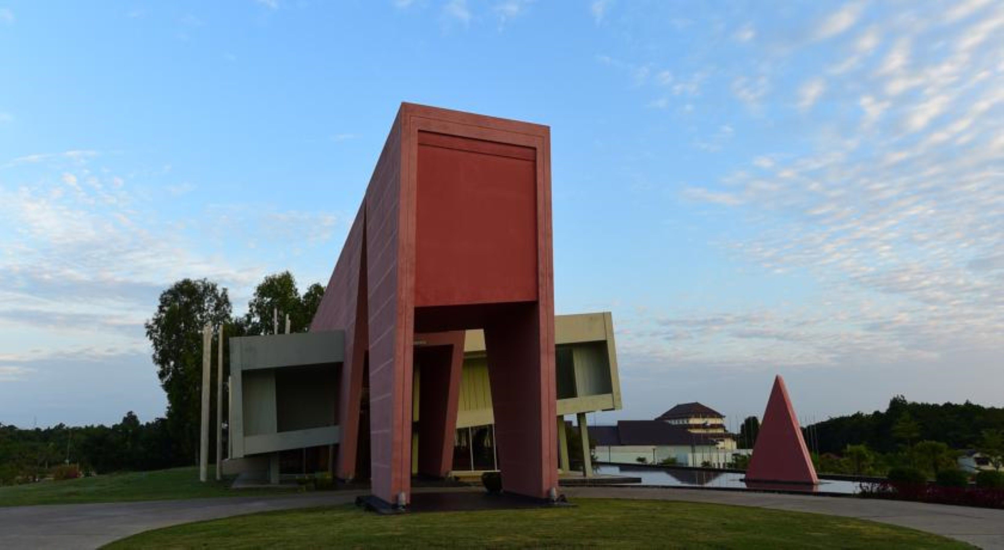 Un bâtiment moderne au design angulaire original, caractérisé par une structure rouge imposante et un toit plat.