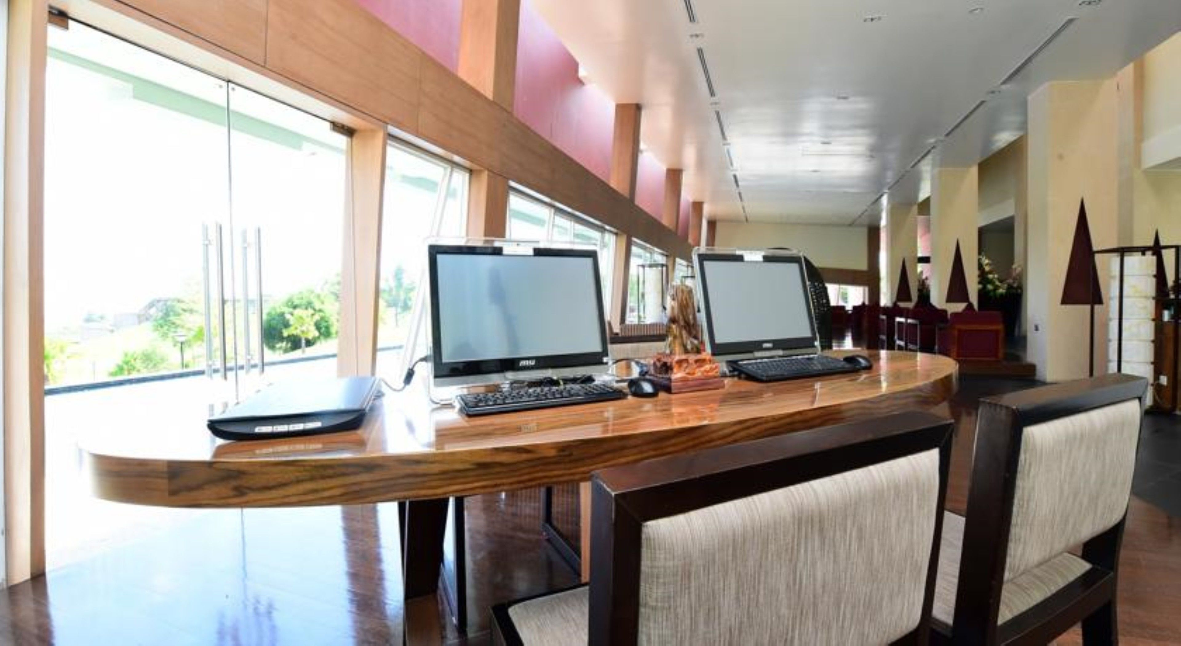 A reception desk with two computer monitors, a laptop, and a keyboard.