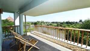 A balcony with a wooden deck, a metal railing, and a view of a river and greenery. - The Thingaha Nay Pyi Taw (Naypyidaw)