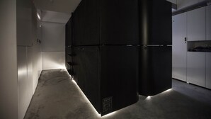 A modern kitchen with a large black refrigerator, white cabinets, and a concrete floor. - SLEEEP Soho (Hong Kong)