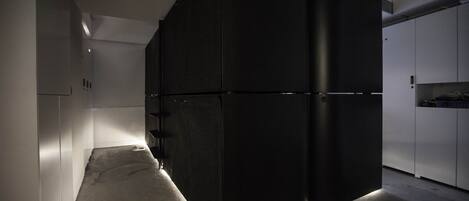 A modern kitchen with a large black refrigerator, white cabinets, and a concrete floor.