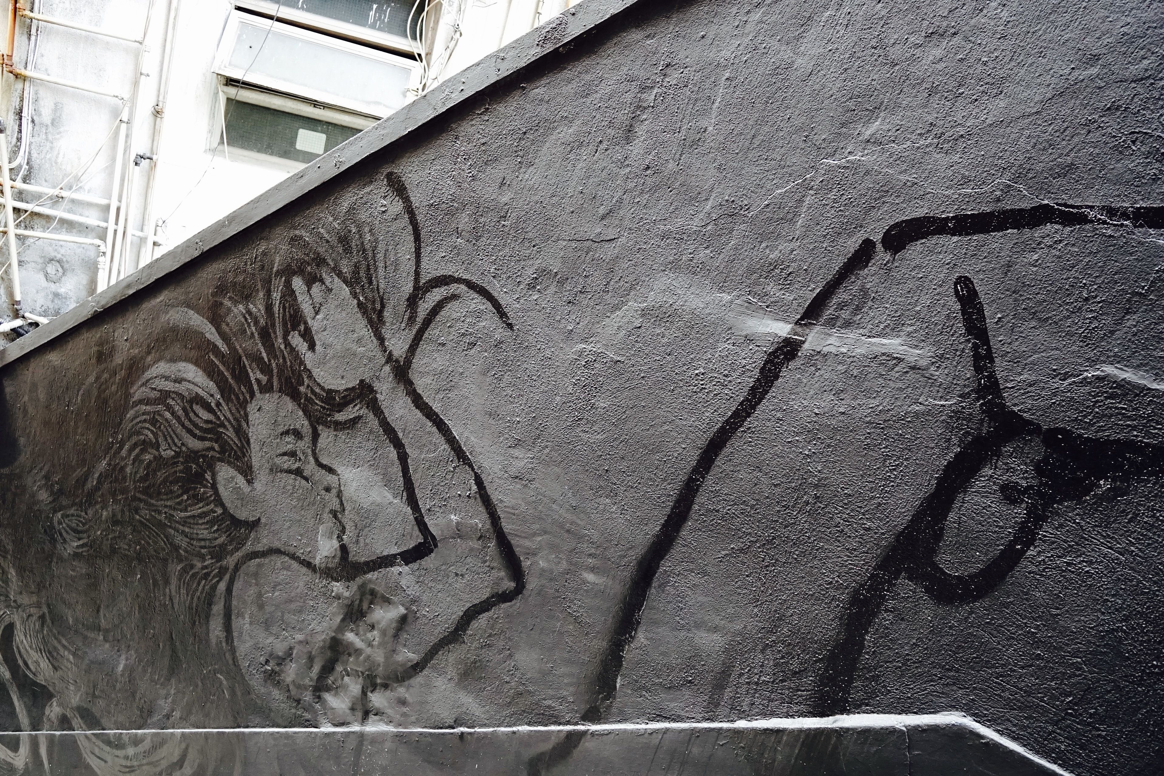 Pared de concreto con grafitis y una vista parcial de un edificio con ventanas.