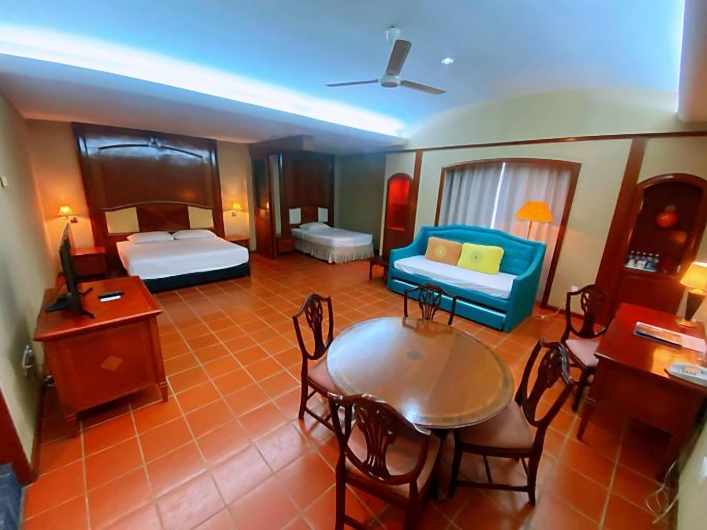 Ein Hotelzimmer mit Bett, Sofa, Esstisch und Fernseher.