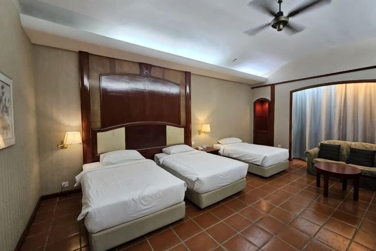 A hotel room with two beds, a sofa, a small table, and a ceiling fan.