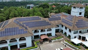 Un bâtiment doté de plusieurs panneaux solaires sur le toit, d’une tour et d’une cour avec une fontaine.