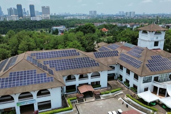 Un bâtiment doté de plusieurs panneaux solaires sur le toit, d’une tour et d’une cour avec une fontaine.