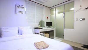 A hotel room with a bed, a desk with a computer, a mirror, and a wardrobe. - Itaewon A One Hotel (Seoul)
