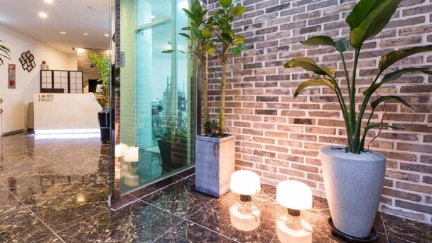 A reception area with a glass door, a brick wall, and potted plants. - Itaewon A One Hotel (Seoul)