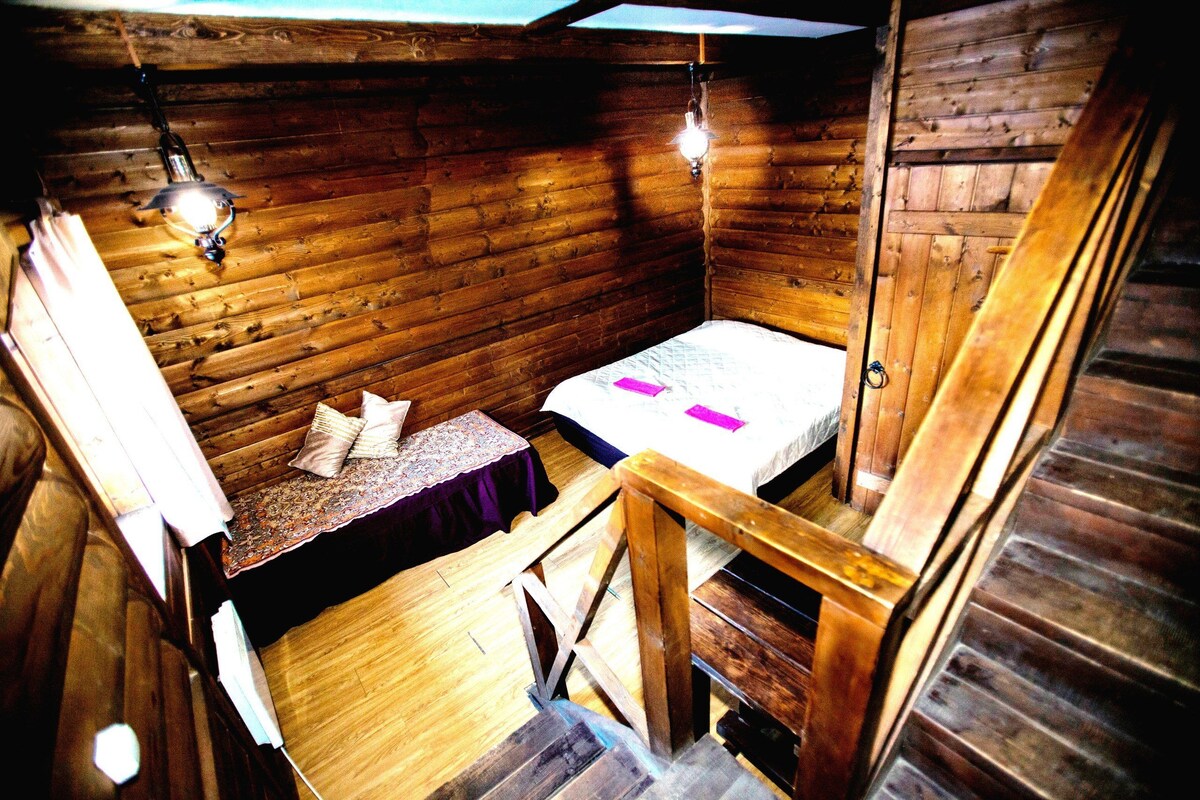 Una pequeña cabaña con una cama, una mesita y un banco.